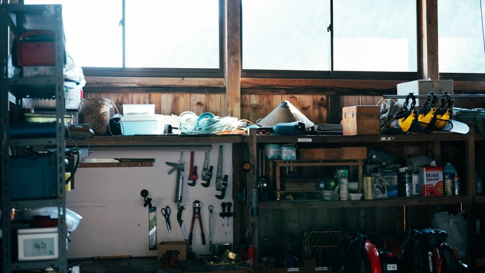 窓から光が入る作業場の棚に、道具や部品が並んでいる